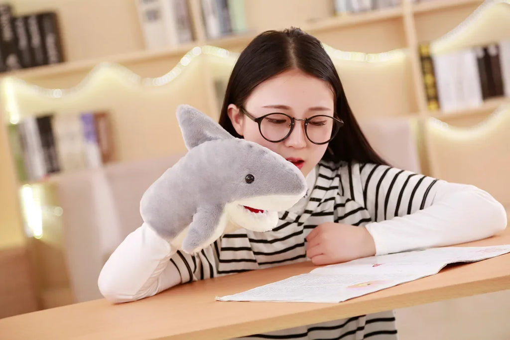 Woman reading with a shark-shaped pillow on a desk in a cozy room.