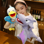 Person holding a plush shark toy with a duck-like character in a home setting.