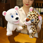 Person holding a plush polar bear and a plush leopard on a wooden surface.