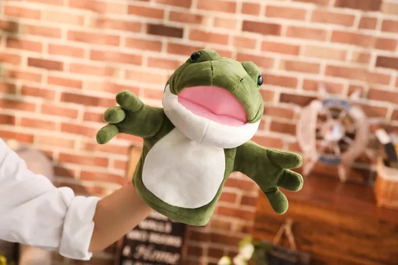 Green frog plush toy held by a person against a brick wall.